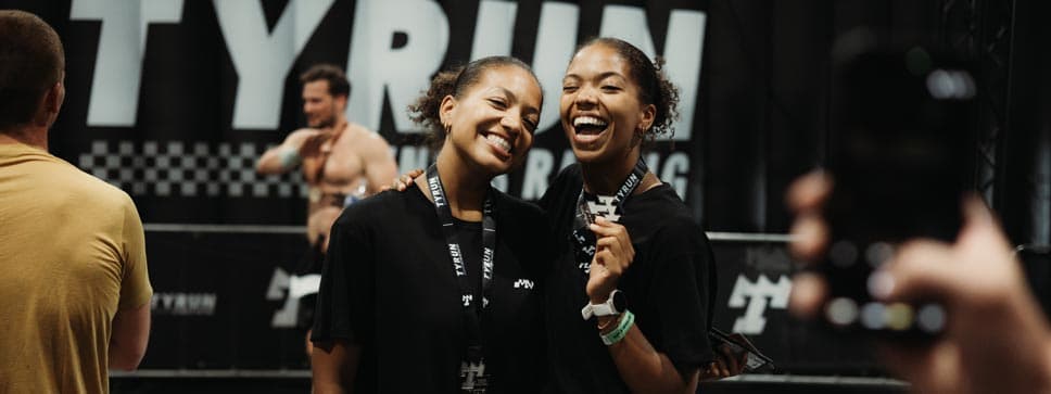 Two athletes smiling with their medals after a TYRUN race